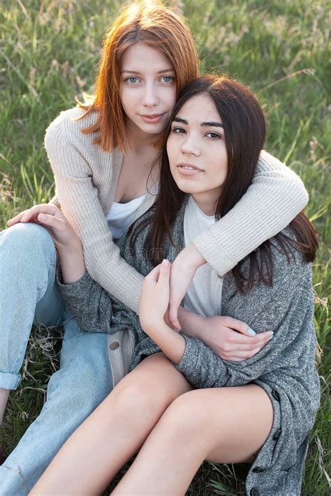 Duas Meninas Bonitos Que Sentam Se Na Grama Foto De Stock Imagem De