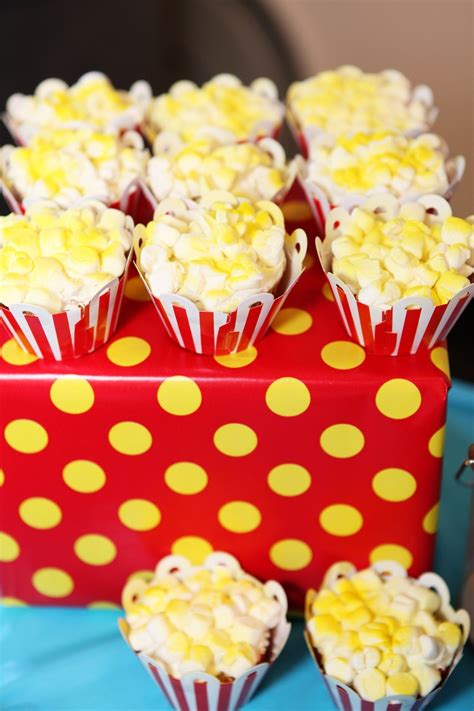 A Red Box Filled With Yellow And White Cupcakes On Top Of A Blue Table