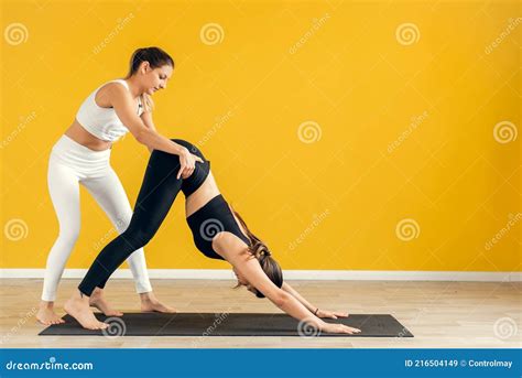 A Young Gymnast Performs A Dog Pose In The Gym Under The Supervision Of