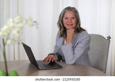 Pretty Older Woman Sitting Table Typing Stock Photo