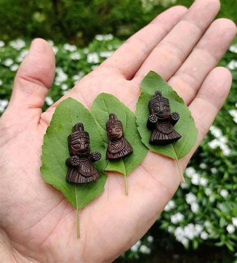 Three Small Figurines Sitting On Top Of Green Leaves In Someone S Hand