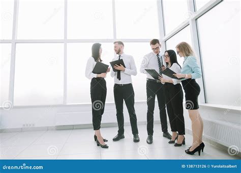 Employees Discuss Business Documents Standing In The Office Lobby Stock