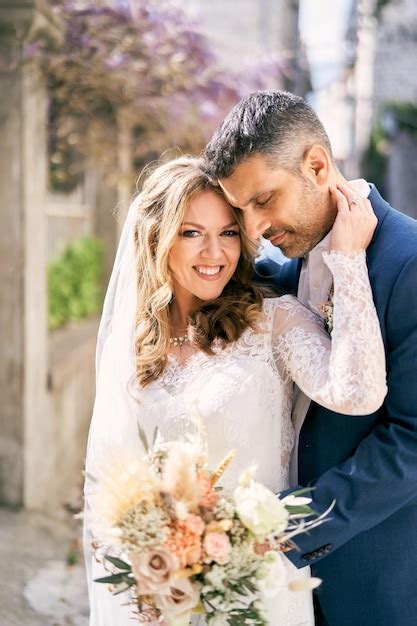 Premium Photo Smiling Bride Touches The Cheek Of The Groom Hugging