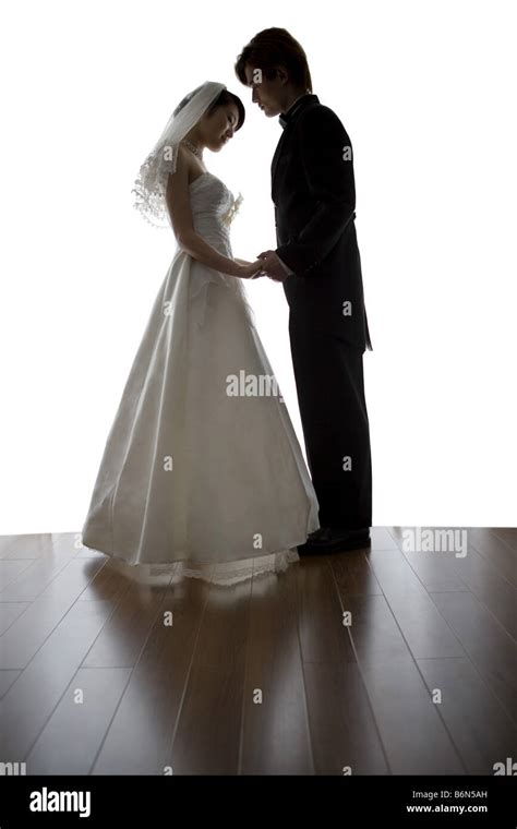 Bride And Groom Standing Face To Face Holding Hands Side View Stock