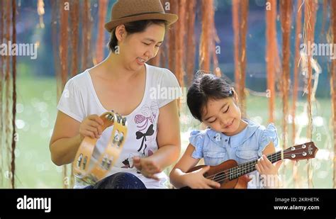 Asian Daughter Playing Ukulele With Her Mother In Park Stock Video