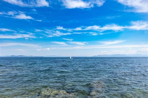 Premium Photo Small Optimist Boat With White Sail Blue Sky And Sea