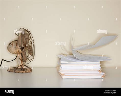 Electric fan blowing on heap of papers Stock Photo - Alamy