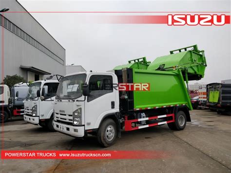 Two Green And White Garbage Trucks Parked Next To Each Other