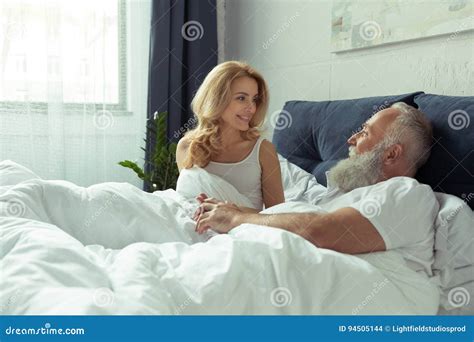 Happy Mature Couple Lying Together In Bed And Smiling Each Other Stock