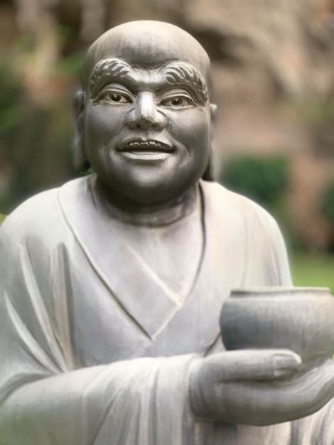 Una Estatua De Un Hombre Con Una Copa Y Una Cara Que Dice Yazu