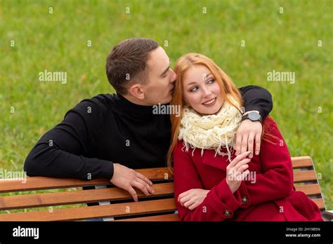 Jeune Couple Romantique Sur Un Banc De Parc Le Gars Chuchote Dans L