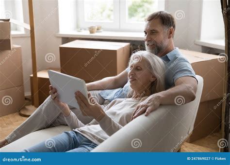 Happy Relaxed Retired Couple Using Graphic App On Tablet Computer Stock