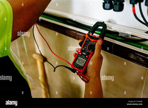 Mature Engineer Examining With Multimeter At System In Utility Room