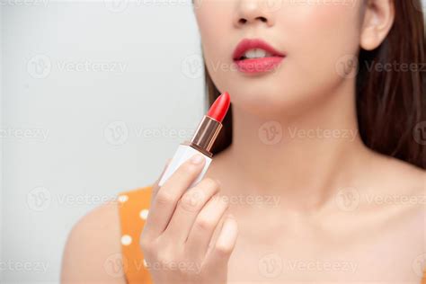 hermosa joven aplicando lápiz labial rojo sobre fondo de color primer