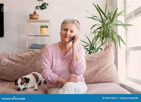 Mature Woman Sitting On Sofa At Home With Mobile Phone Stock Image Image Of Lady Cozy 260170821
