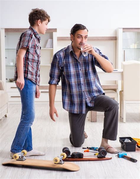 Padre Joven Arreglando Patineta Con Su Hijo En Casa Imagen De Archivo