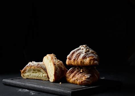 Croissants horneados en una tabla de madera negra salpicados de azúcar