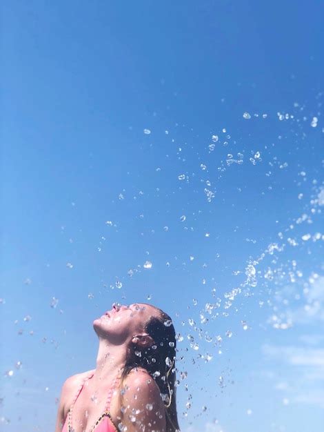 Premium Photo Woman Splashing Water Against Clear Blue Sky