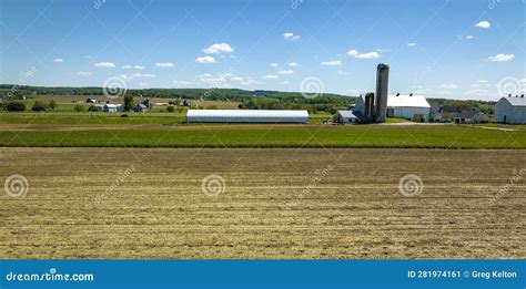 Aerial View Of A Plowed Field With A Barn Silos And Farm House In View