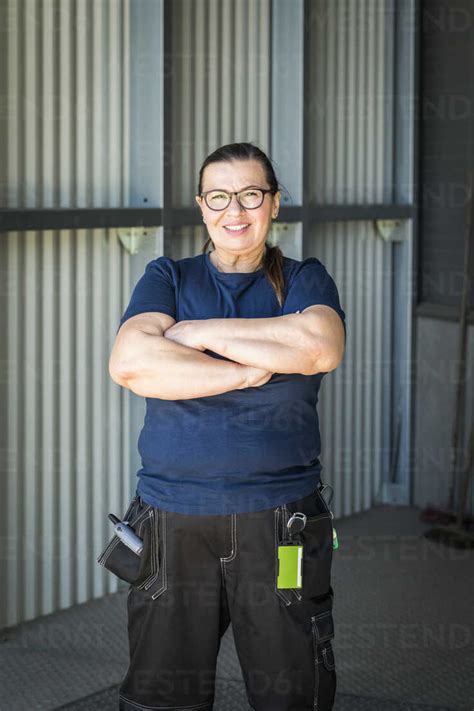 Portrait Of Smiling Mature Female Worker Standing With Arms Crossed On