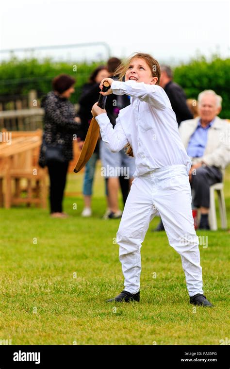 Young girl, child, 12-13 years, batting with cricket bat while dressed ...