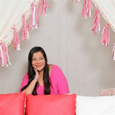 Mujer latina adulta con el pelo largo y liso en suéter rosa es feliz y cómoda en un picnic bajo