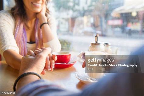 Smiling Couple Holding Hands And Drinking Coffee In Cafe Photos And