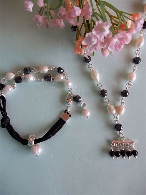 Two Bracelets With Black Beads And White Pearls Are On A Table Next To