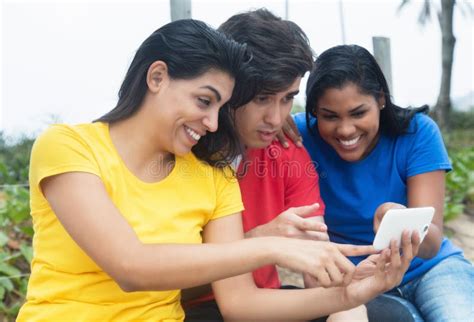 Mujer Latina Que Mira Selfies El Teléfono Con El Hombre Caucásico Y La Muchacha Nativa Foto de