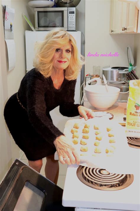 A Woman In A Black Dress Is Holding A Cookie Sheet And Making Cookies