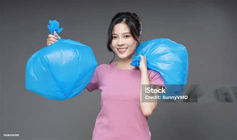 Young Asian Woman Holding Trash Bag On Background Stock Photo