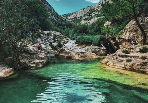 People Are Swimming In The Water Near Some Rocks