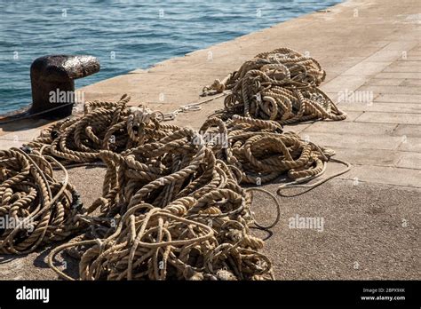 Cuerdas De Amarre En Un Viejo Bolardo De Metal Y El Mar Azul Claro En