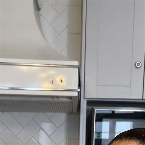 A Woman Taking A Bite Out Of A Pizza In The Kitchen With An Oven Behind Her