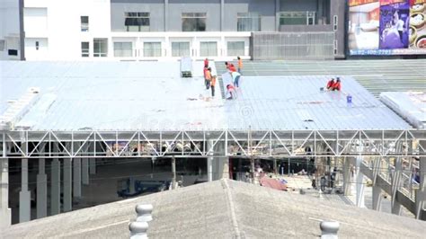 Workers Roofing Metal For The Roof On A Large Commercial Building At