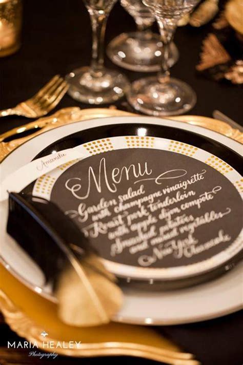 A Black And Gold Table Setting With Menus