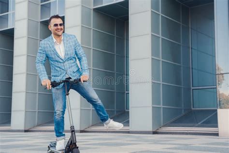 Glad Man Riding Scooter In City Around Huge Building Stock Image