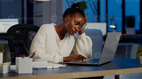 Exhausted african freelancer resting head on hand in front of laptop