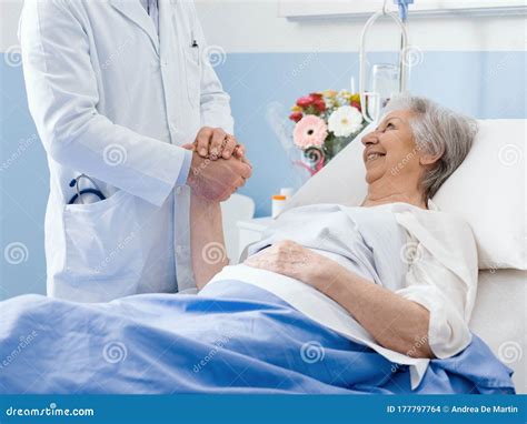 Doctor Visiting An Elderly Patient And Comforting Her Stock Photo