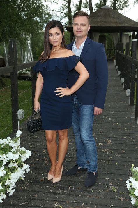 A Man And Woman Standing Next To Each Other On A Bridge With Flowers In