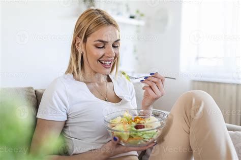 Mujer Joven Y Feliz Comiendo Ensalada Saludable Sentada En El Sofá Con