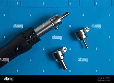 Hot Air Gun For Soldering And Additional Attachments To It On The Background Of A Blue Mat
