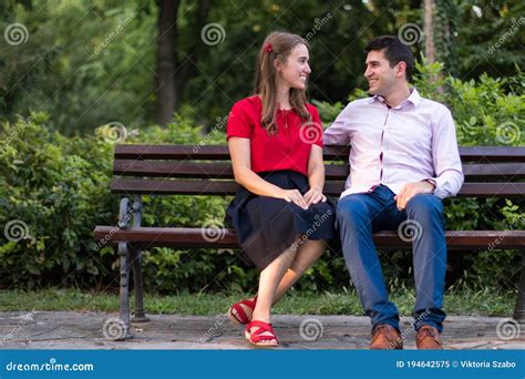 Pareja Joven Hablando En El Parque Sentada En Un Banco Imagen De