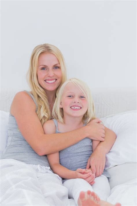 Curly Blonde Mother And Daughter Lays On Bed Together Stock Photo