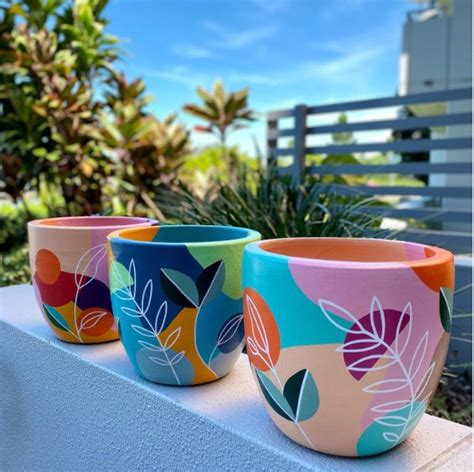 Three Colorful Flower Pots Sitting On Top Of A White Ledge