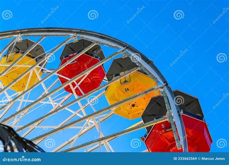 A Tall Metal Ferris Wheel With Colorful Cars Around The Wheel On With