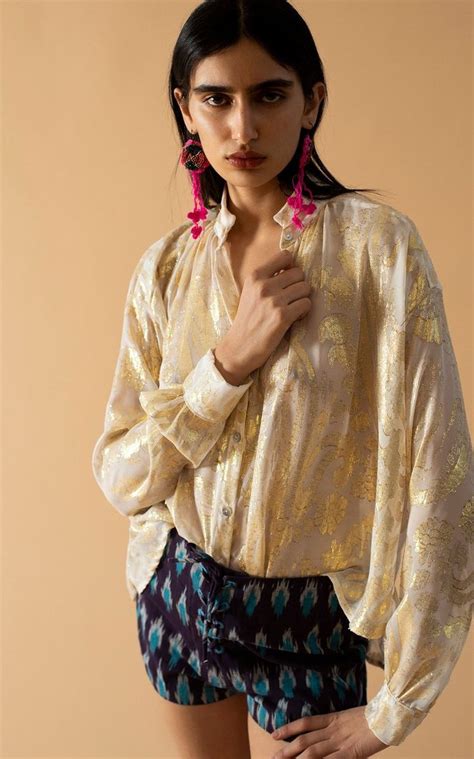 A Woman In Shorts And A Blouse Posing For The Camera With Her Hands On