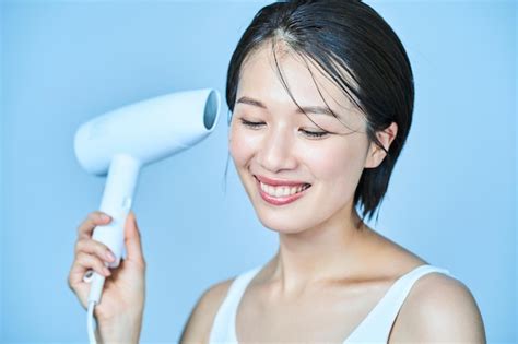 Premium Photo A Woman Drying Her Hair With A Hair Dryer