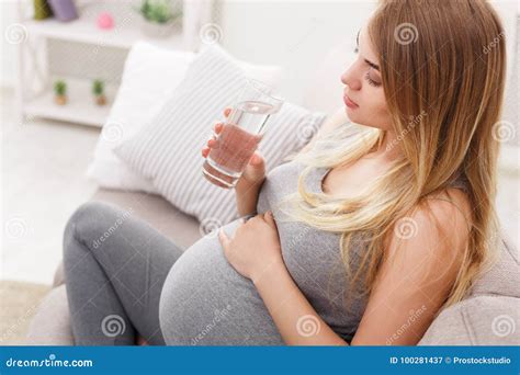 Pregnant Woman With Glass Of Water Sitting On Sofa Closeup Stock Image