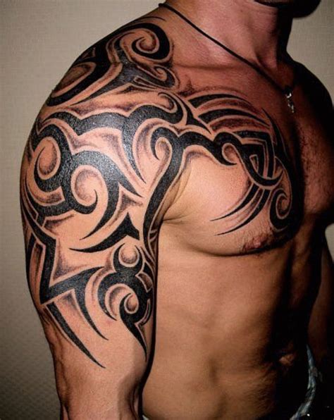 A Man With A Tattoo On His Arm And Chest Is Looking At The Camera While Standing In Front Of A Wall